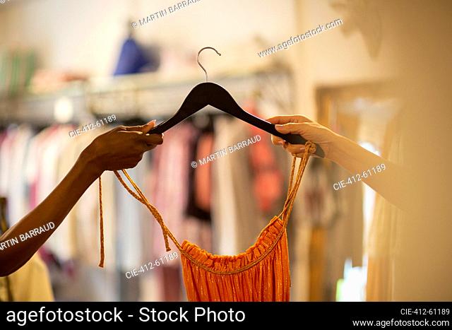Woman handing dress on hanger to customer in shop