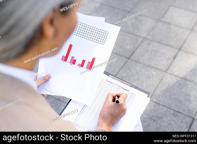 Businesswoman preparing strategies while writing on paper