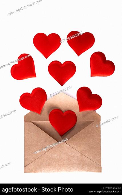 Valentine day love letter, envelope of craft paper with red hearts heap spread on white background