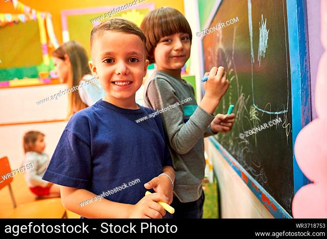 Kinder malen mit Kreide an der Tafel in der Vorschule oder Grundschule im kreativen Malkurs