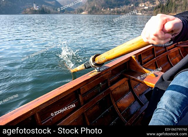 Young woman using paddle on a wooden boat - Lake Bled Slovenia rowing on wooden boats on a sunny day