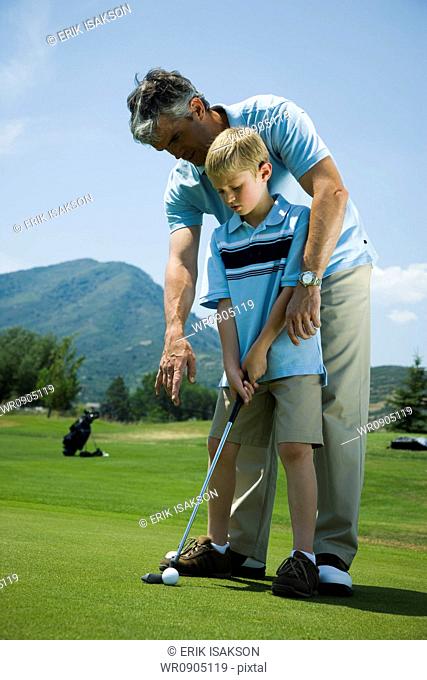 Father teaching his son to play golf