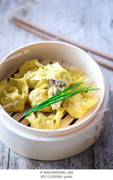 Won tons with chives in a bamboo steamer