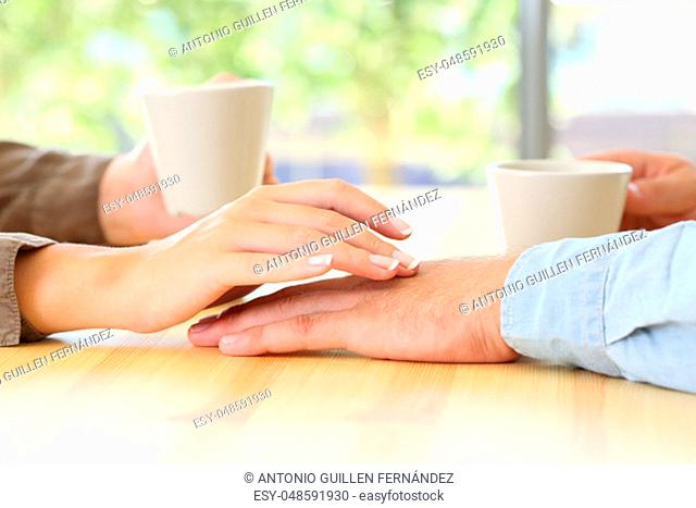 Close up of a couple dating and touching hands in a bar or house