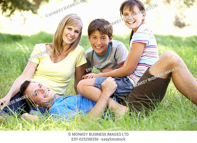 Family Relaxing In Summer Field