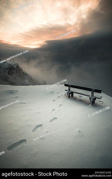 bench in the snow on a mountain peak in winter in the austrian alps