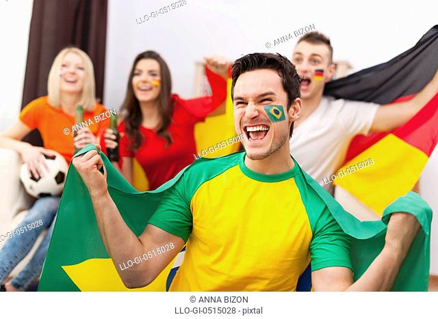 Excited brazilian man with her friends cheering football match. Debica, Poland