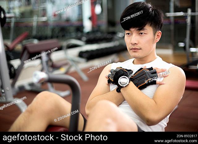 young handsome asian man works out in modern gynm