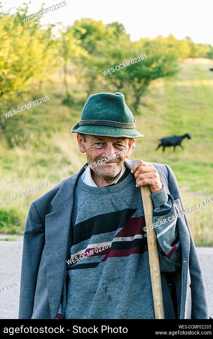 Senior male goat herder holding cane
