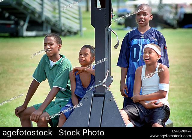 Four 12 year old black african american youths wait thurn to play basketball