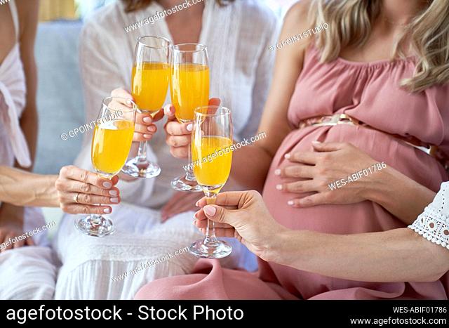 Hands of women toasting cocktail glasses at baby shower