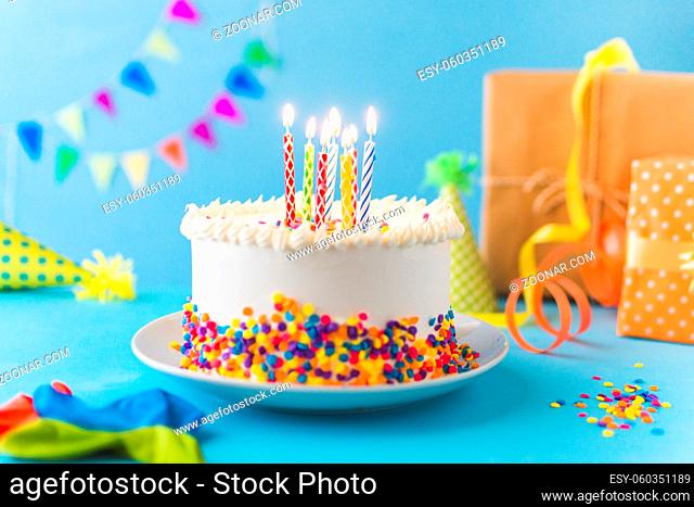 decorative cake with burning candle blue background