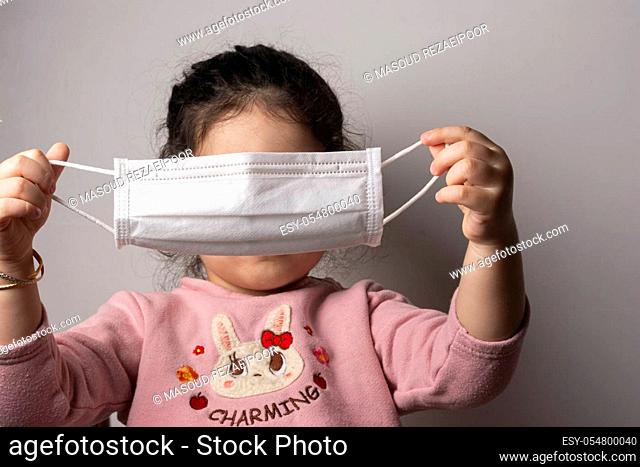 Little girl trying to wear a mask for protection from epidemic coronavirus, coronavirus outbreak and air pollution concept