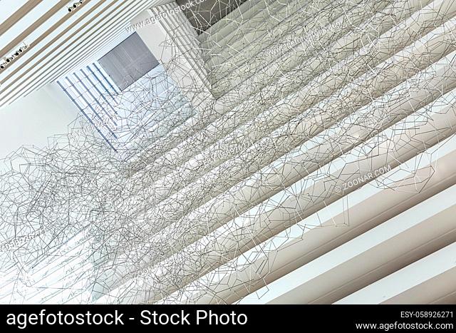 View from below on the installation of the wicker wire geometric figures on the white wall background in the Marina Bay Sands Hotel in Singapore