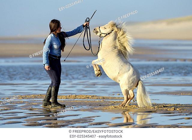 Young lady riding a pony on the beach in early morning, France