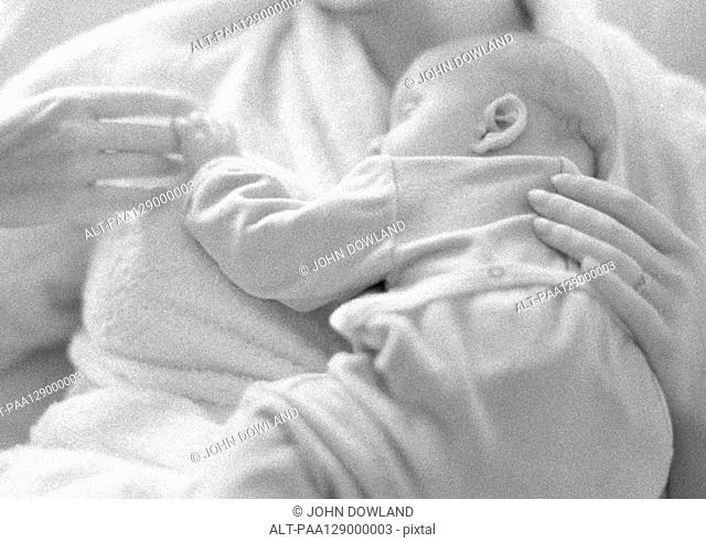 Mother holding sleeping infant on chest, b&w