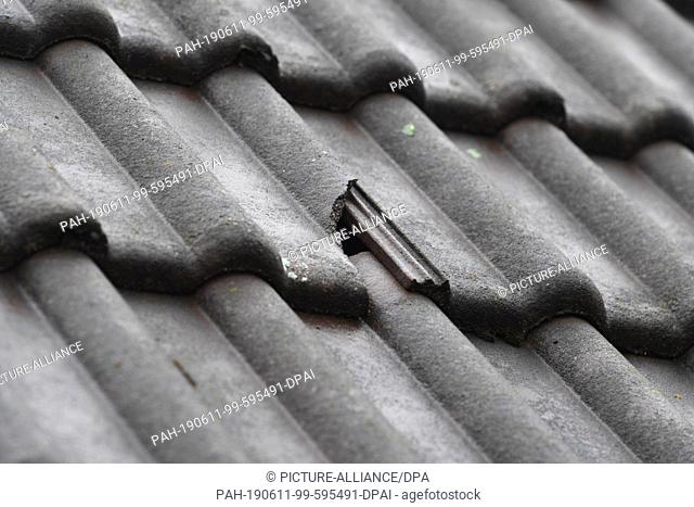 11 June 2019, Bavaria, München -Neuaubing: A roof damaged by hail on a house in Neuaubing has a broken brick. Craftsmen will have to repair the damage caused by...