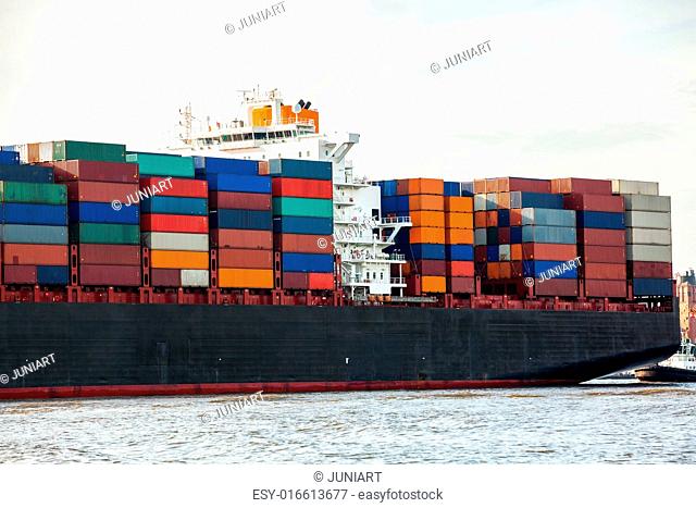 Fully laden container ship in port with its decks stacked with metal containers full of freight and cargo for international destinations