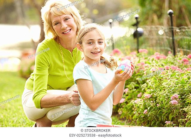Grandmother With Granddaughter On Easter Egg Hunt In Garden