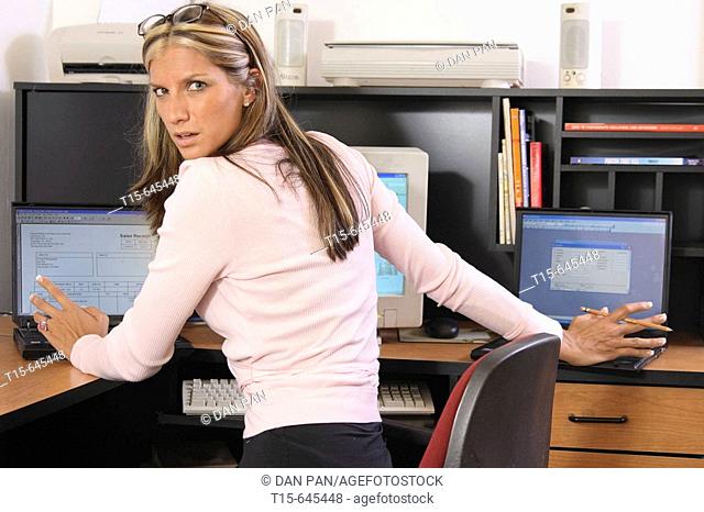 Woman in her 20's caught stressed out busy working on different tasks on multiple computers