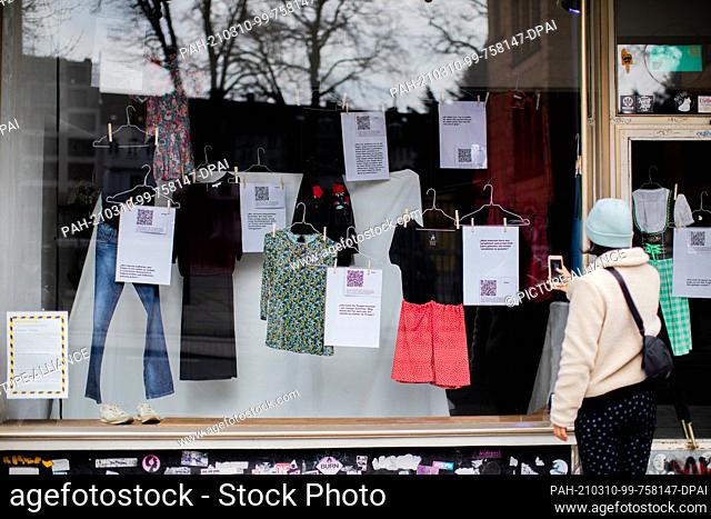 08 March 2021, North Rhine-Westphalia, Aachen: Student Jasmin looks at pieces of clothing worn by women who have suffered sexualised violence in a shop window...