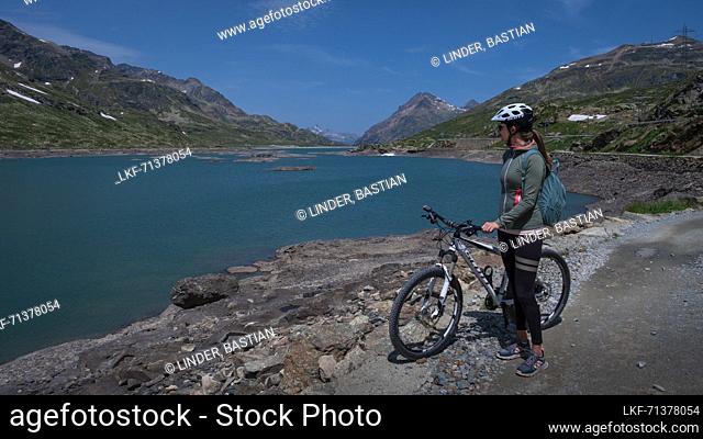 Mountain biking at the Lago Bianco reservoir at the Bernina Pass in the sun