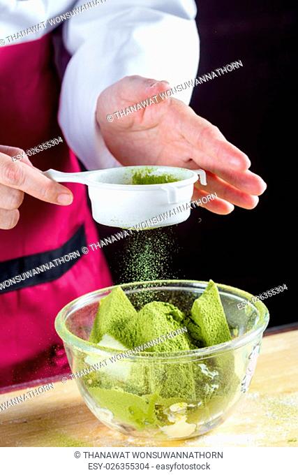 Chef sifting flour into pastry molds for making green tea cake