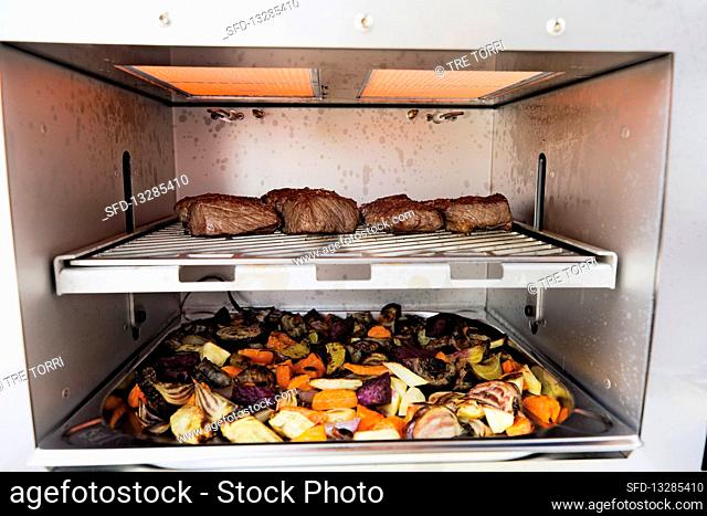 Meat and oven-roasted vegetables being grilled in a Beefer