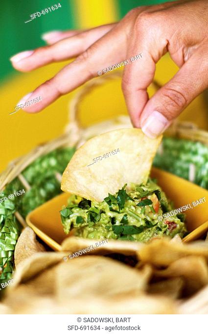 Hand Dipping Tortilla Chip into Guacamole