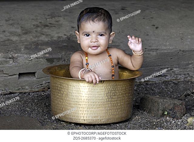 Warli tribal baby bathing in the brass vessel