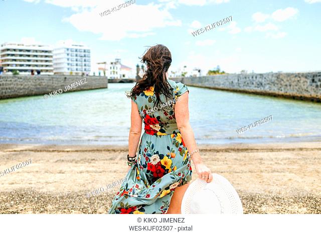 Rear view of woman with white sun hat at harbour in Arrecife, Spain