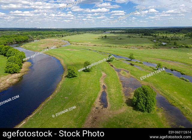 Aerial view of winding river bed with ducts. Flying above swampy plain