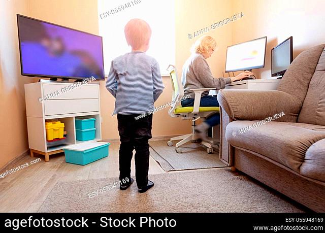 woman working at home with little child. Young businesswoman working indoors at pc