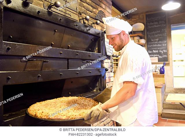 Master baker Alexander Mikat takes Streuselkuchen (crumb cake) from a wood-fired oven in the organic bakery of the Schmilka Mill in the Schmilka district of Bad...