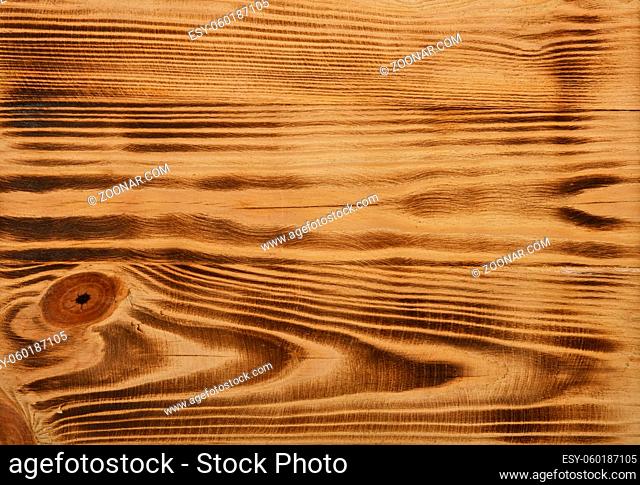 Close up background texture of vintage weathered burnt and brushed pine wood surface with knots and stains