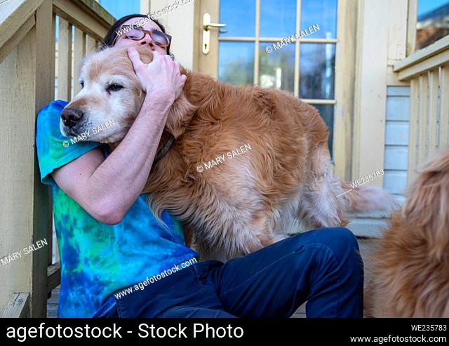 Happy image of a golden retriever dog and a man relaxing together on back porch steps of a residential home. Comfortable relationship