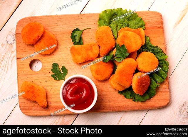 Breading chicken breast nuggets and sauce for choice on wooden background