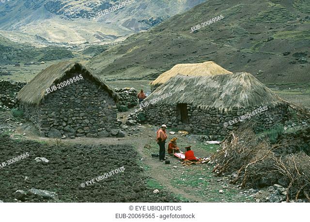 Local Quechuan people weaving in front of dwelling
