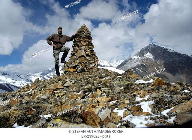 Mountaineer at stone pile on 5237 m high peak with some snow Phu Nar-Phu Annapurna Region Nepal