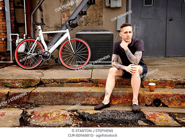 Portrait of young tattooed man on steps