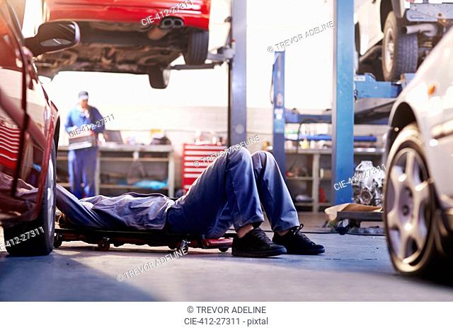 Mechanic under car in auto repair shop
