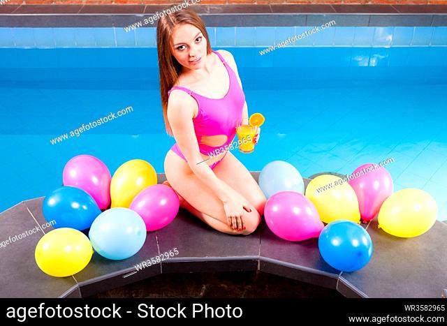 Relax, spa wellness concept. Happy woman having fun with balloons and cocktail drink alcohol. Pretty girl relaxing at swimming pool edge poolside