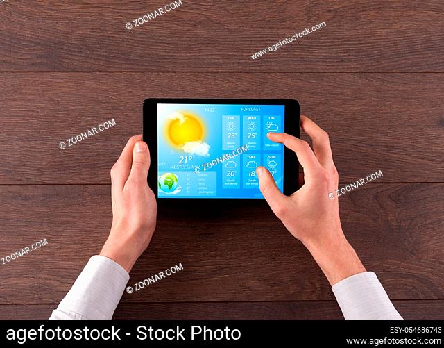 Man hand checking weekly weather forecast on tablet