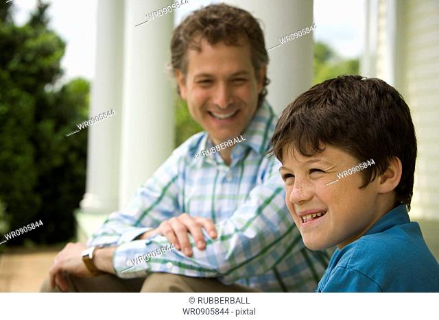 Close-up of a boy and his father smiling