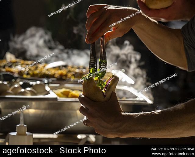 02 October 2022, Brandenburg, Potsdam: A man prepares Sabich in Pita, a traditional Jewish dish, at the Jewish Street Festival