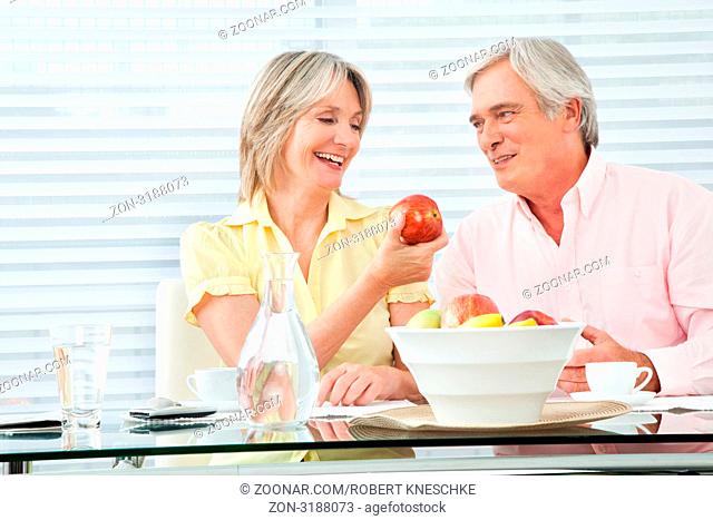 Seniorin bietet ihrem Mann einen Apfel an
