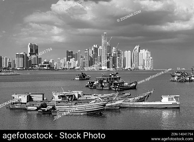 old wooden fishing boats in front of the skyline of panama city panama in black and white