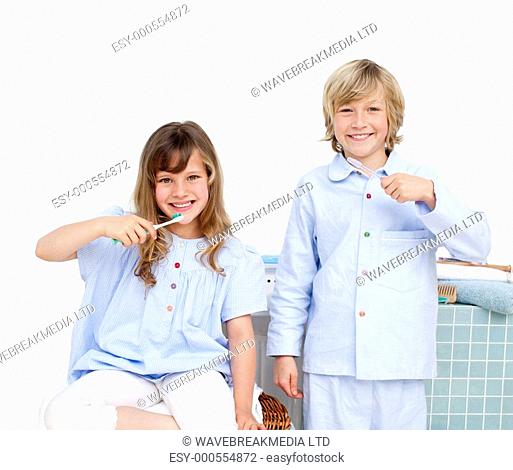 Smiling brother and siter brushing their teeth at home