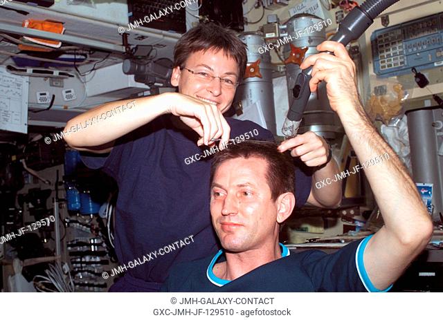 Astronaut Peggy A. Whitson, Expedition Five flight engineer, cuts cosmonaut Sergei Y. Treschev's hair in the Zvezda Service Module on the International Space...