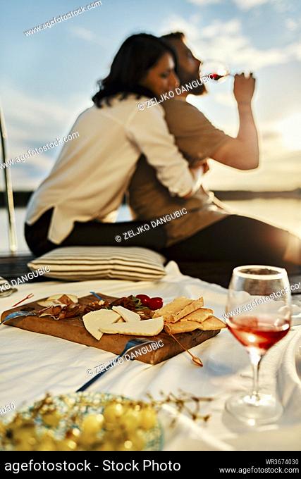 Couple having picnic on jetty at a lake at sunset